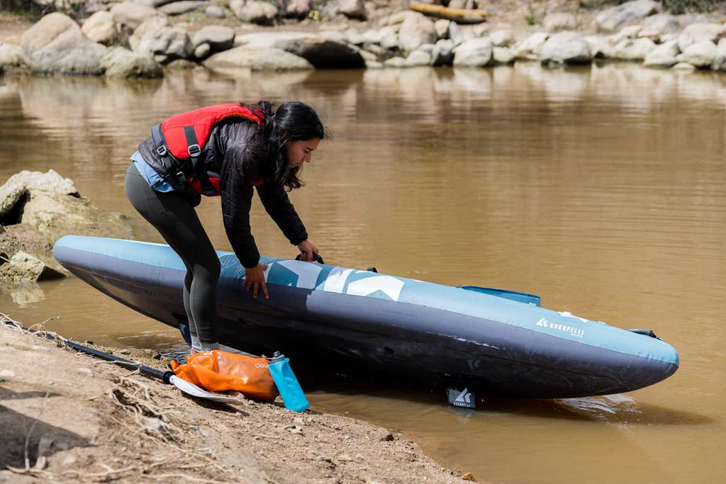 Woman picks kayak up out of muddy water before cleaning