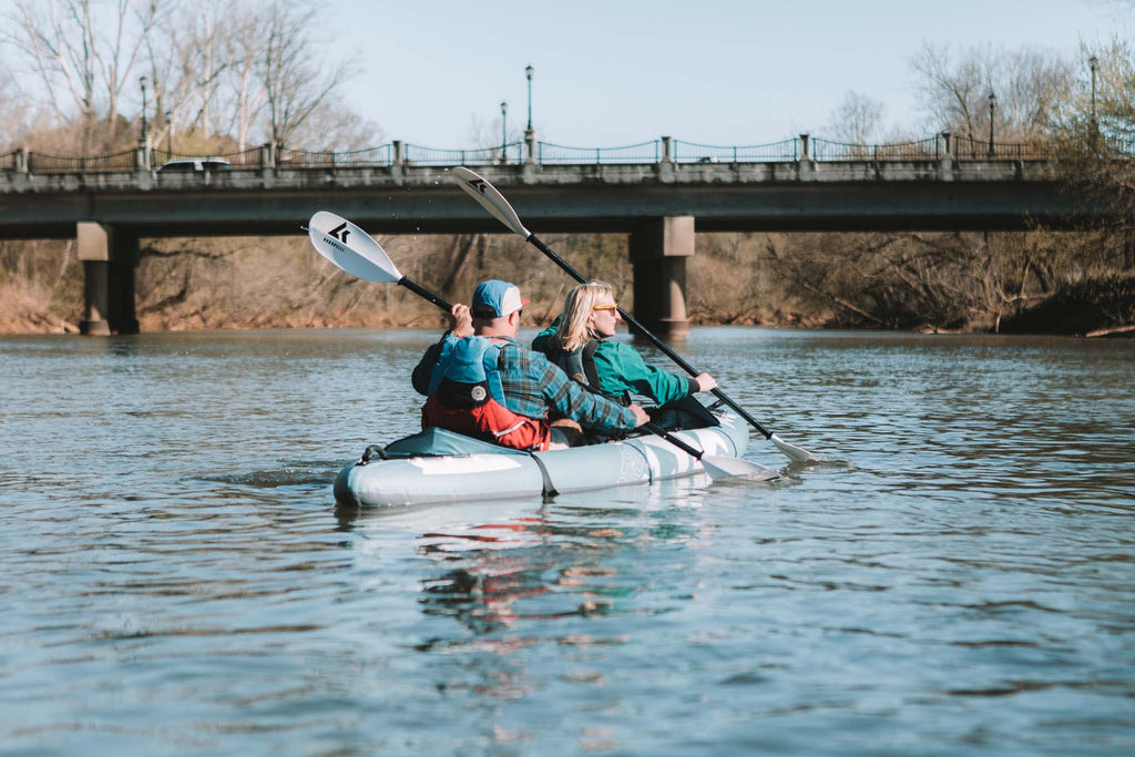 Middle-aged couple with red life vests sits in an aqua tandem kayak.