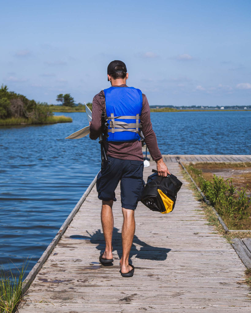 Man carrying compacted Rogue-Lite Packraft on boardwalk