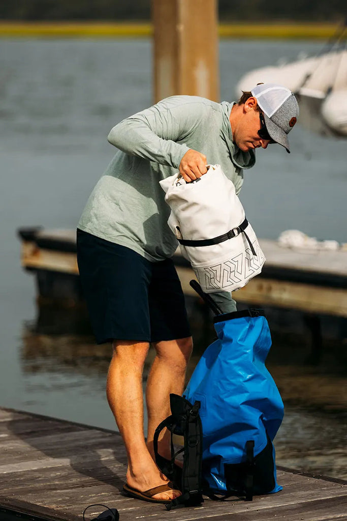 Man placing compacted Chasm-Lite Inflatable SUP in bag